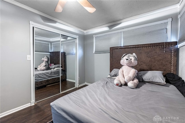 bedroom featuring a closet, baseboards, dark wood-style floors, a textured ceiling, and ornamental molding