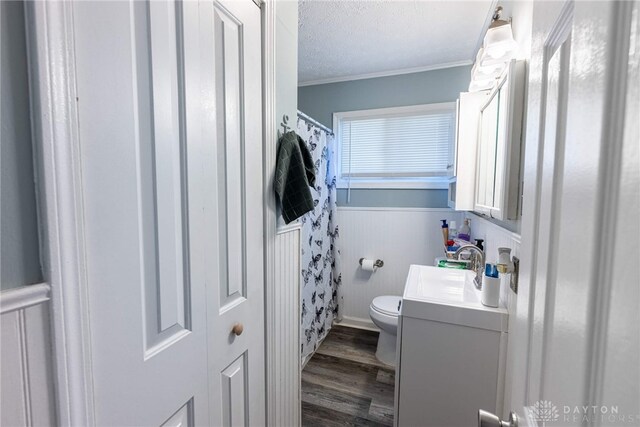 bathroom with wood-type flooring, ornamental molding, toilet, a textured ceiling, and vanity