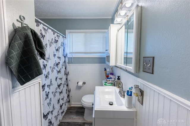 full bathroom featuring a wainscoted wall, a textured ceiling, radiator, vanity, and wood finished floors