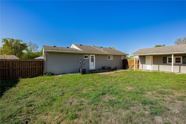 rear view of property with a fenced backyard and a lawn