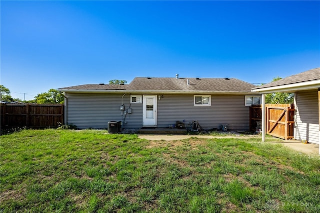 rear view of house with a gate, fence, central AC, and a yard