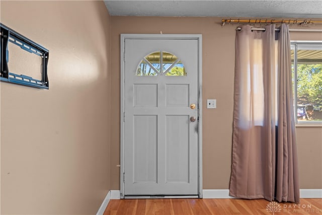 entryway with light wood-type flooring and a textured ceiling