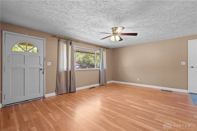 foyer entrance with light wood-type flooring, a textured ceiling, plenty of natural light, and ceiling fan