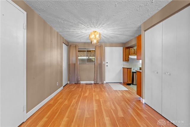 interior space featuring light wood-type flooring, a chandelier, a textured ceiling, and tasteful backsplash