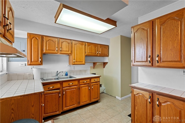 kitchen featuring tile counters, sink, a textured ceiling, and light tile patterned flooring