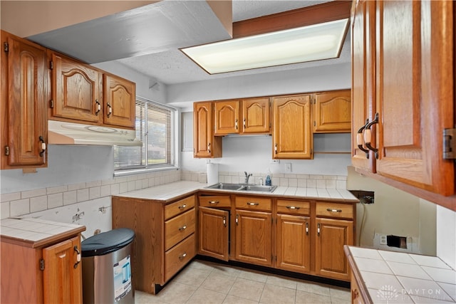 kitchen featuring tile countertops, light tile patterned floors, and sink