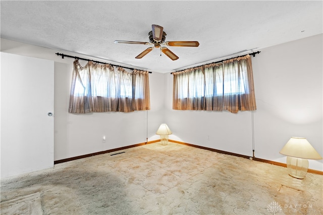 carpeted spare room featuring ceiling fan, a textured ceiling, and a healthy amount of sunlight