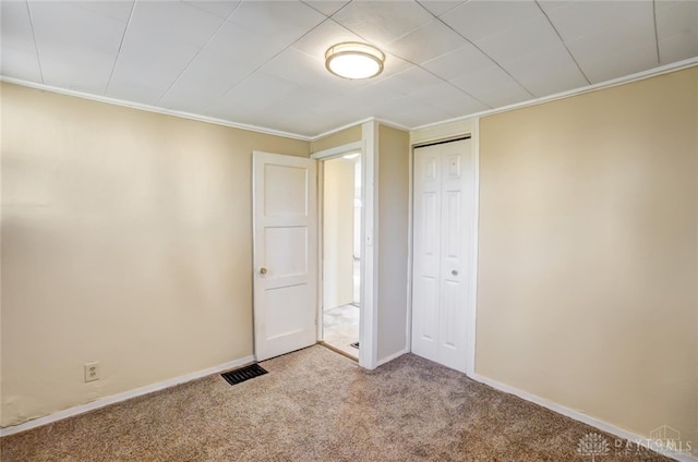 unfurnished bedroom with light colored carpet, a closet, and ornamental molding