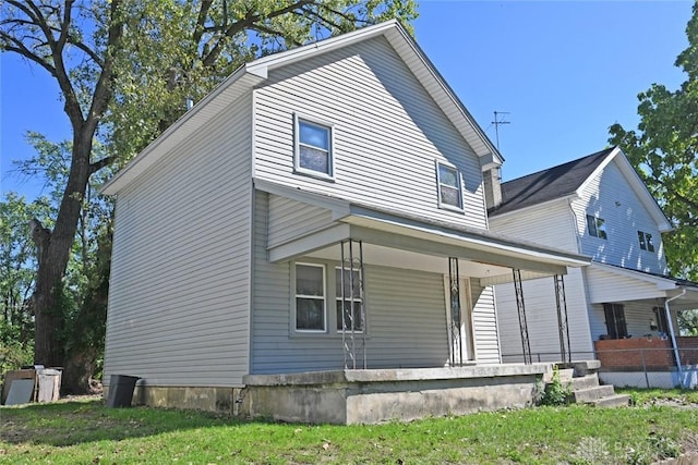 back of property with a porch and a yard