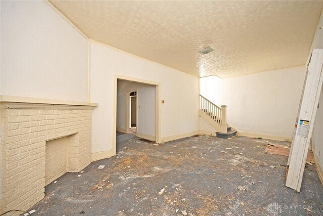 unfurnished living room with a fireplace and a textured ceiling