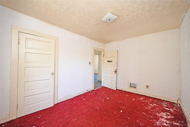 carpeted spare room with a textured ceiling