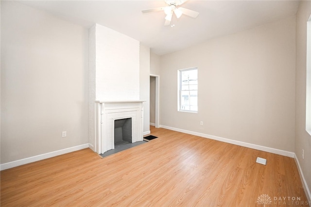 unfurnished living room with light hardwood / wood-style flooring, ceiling fan, and a fireplace