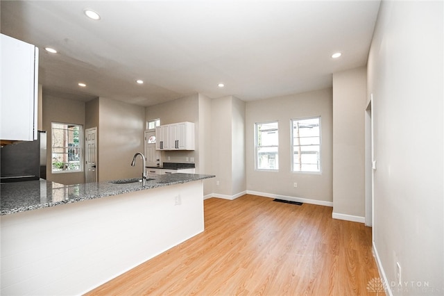 kitchen featuring white cabinetry, stone counters, a healthy amount of sunlight, and sink