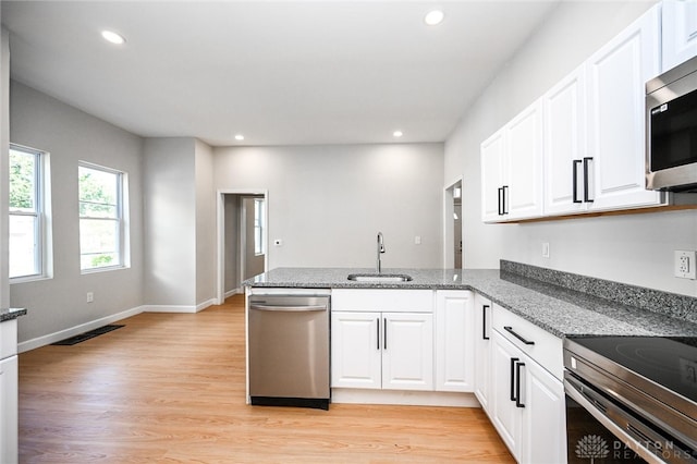 kitchen featuring white cabinets, kitchen peninsula, stainless steel appliances, and sink