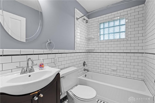 full bathroom featuring vanity, tiled shower / bath, tile patterned flooring, toilet, and tile walls