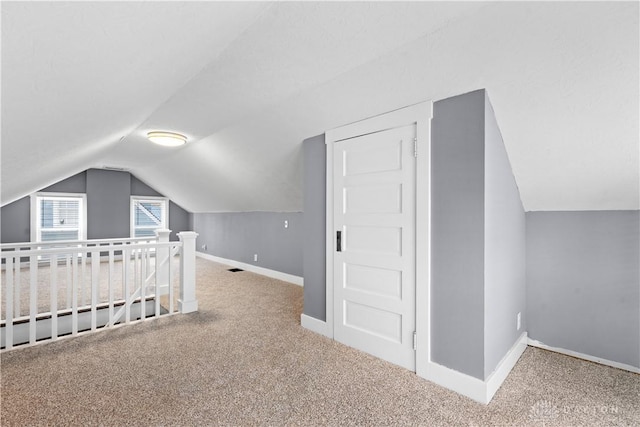 bonus room with carpet flooring and vaulted ceiling