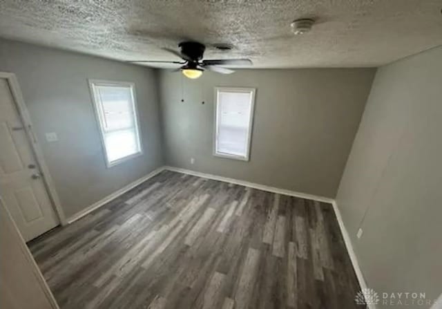 unfurnished room with a textured ceiling, ceiling fan, and dark hardwood / wood-style flooring