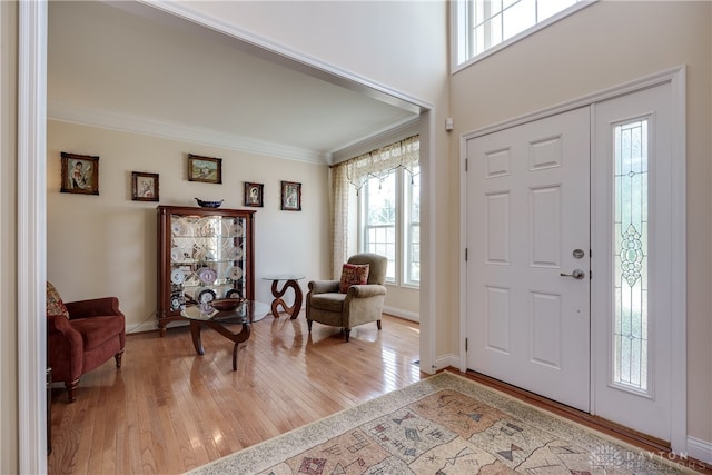 foyer with ornamental molding and light hardwood / wood-style floors