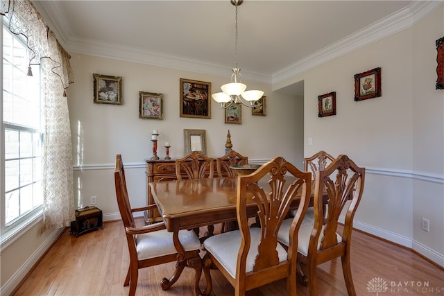 dining space featuring ornamental molding, a chandelier, and light hardwood / wood-style flooring