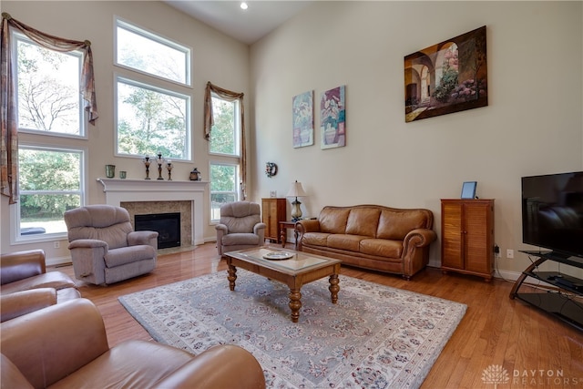 living room featuring light wood-type flooring, plenty of natural light, and a high ceiling