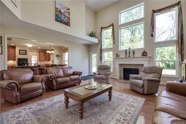 living room with light wood-type flooring, plenty of natural light, and a high ceiling