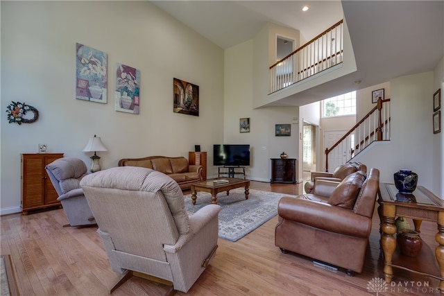 living room featuring light wood-type flooring and a high ceiling