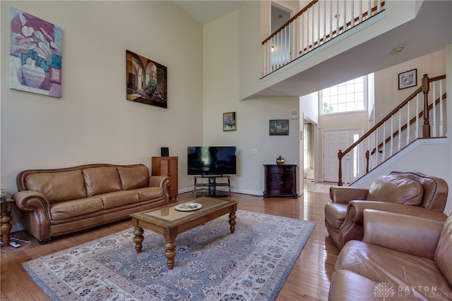 living room with hardwood / wood-style flooring and a towering ceiling