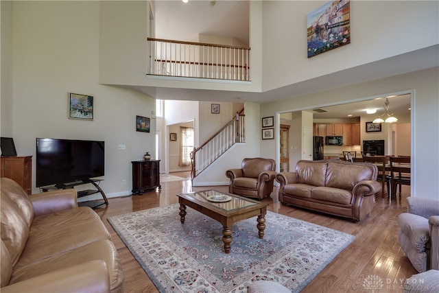 living room with a high ceiling, an inviting chandelier, and light wood-type flooring