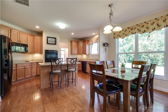 dining room with light wood-type flooring and an inviting chandelier