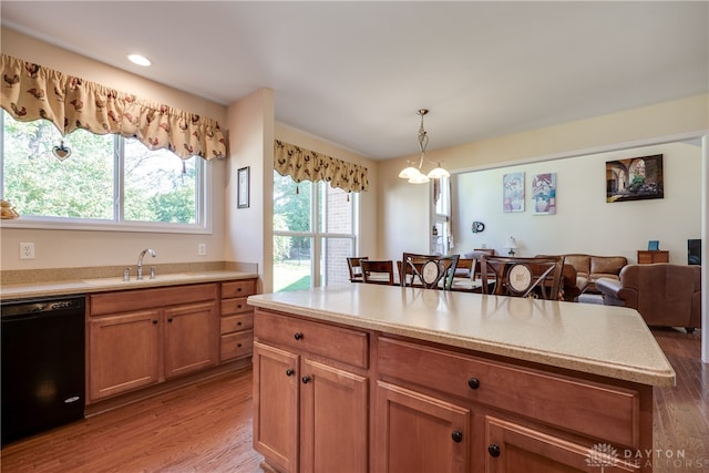 kitchen with pendant lighting, black dishwasher, sink, and light wood-type flooring