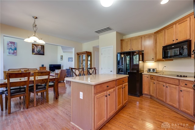 kitchen with light hardwood / wood-style floors, decorative light fixtures, black appliances, and a center island