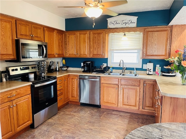 kitchen with a textured ceiling, appliances with stainless steel finishes, ceiling fan, and sink