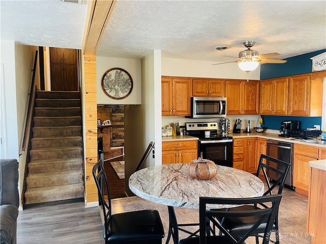 kitchen featuring a textured ceiling, ceiling fan, stainless steel appliances, and hardwood / wood-style flooring