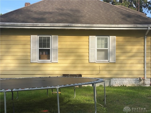 view of property exterior featuring a trampoline and a yard