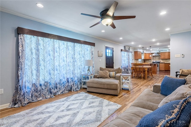 living room with light hardwood / wood-style flooring, ceiling fan, and ornamental molding