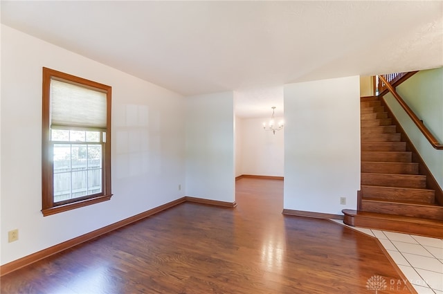 unfurnished room featuring wood-type flooring and an inviting chandelier