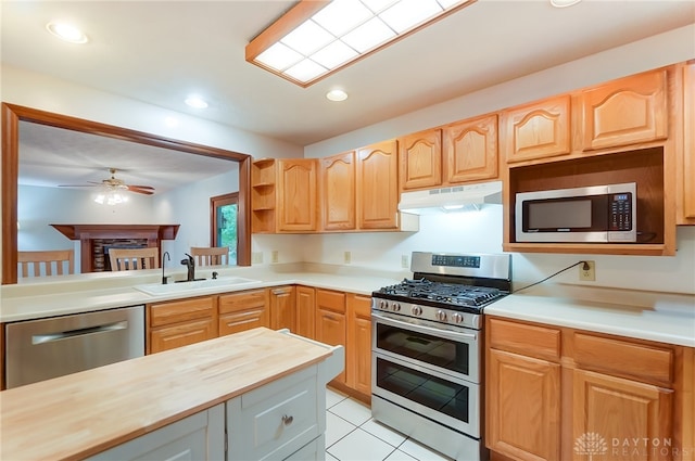 kitchen with light tile patterned flooring, sink, appliances with stainless steel finishes, wooden counters, and ceiling fan