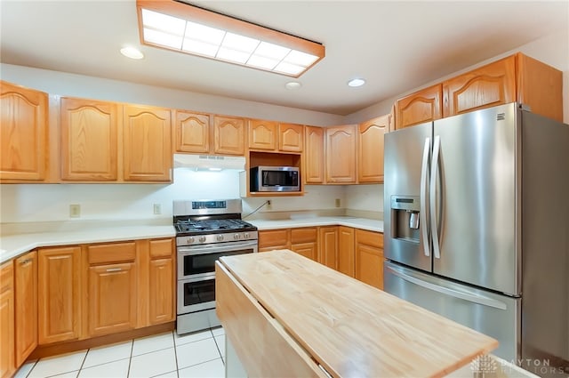 kitchen featuring appliances with stainless steel finishes, wood counters, and light tile patterned floors