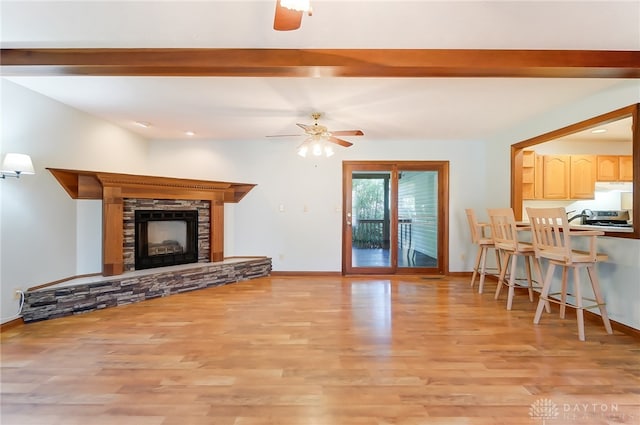 living room featuring ceiling fan, light hardwood / wood-style flooring, and a fireplace