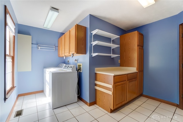 washroom with washing machine and dryer, light tile patterned flooring, and cabinets