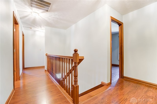 hall with a textured ceiling and light hardwood / wood-style floors