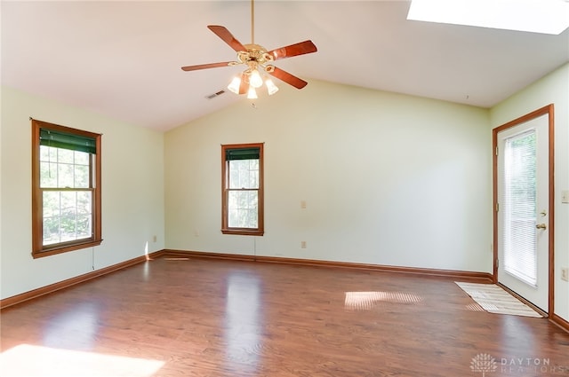 empty room with a healthy amount of sunlight, dark hardwood / wood-style floors, and vaulted ceiling with skylight