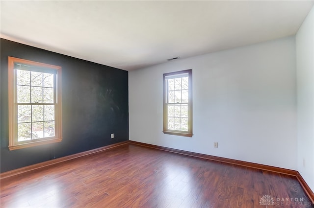 empty room featuring a wealth of natural light and dark hardwood / wood-style floors