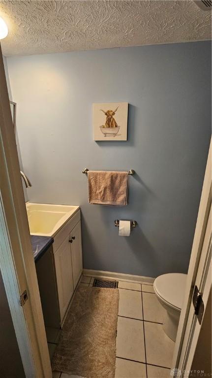 bathroom with toilet, a textured ceiling, tile patterned floors, and vanity