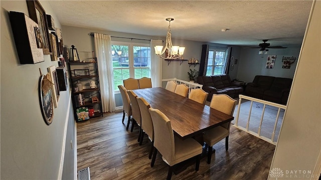 dining area featuring a textured ceiling, dark wood-type flooring, and ceiling fan with notable chandelier