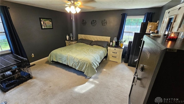 bedroom with ceiling fan, light colored carpet, and a textured ceiling