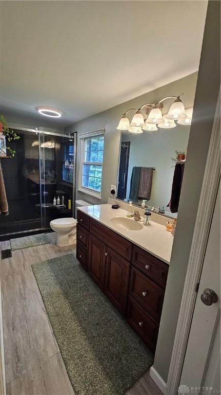 bathroom featuring walk in shower, hardwood / wood-style floors, vanity, and toilet