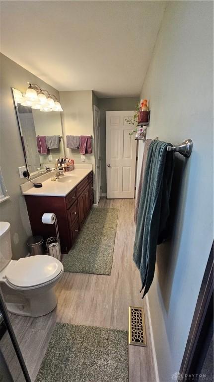 bathroom with toilet, vanity, and hardwood / wood-style flooring