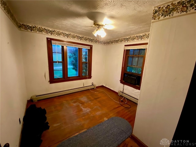 spare room with a baseboard radiator, ceiling fan, hardwood / wood-style floors, and a textured ceiling