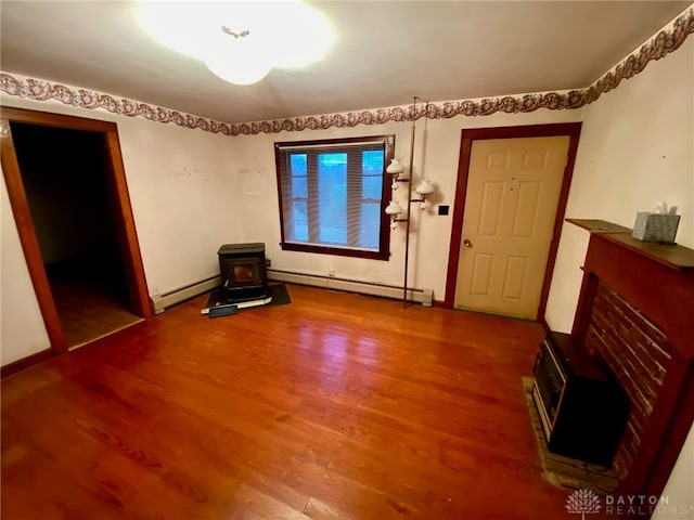 unfurnished living room with wood-type flooring, a baseboard radiator, and a wood stove